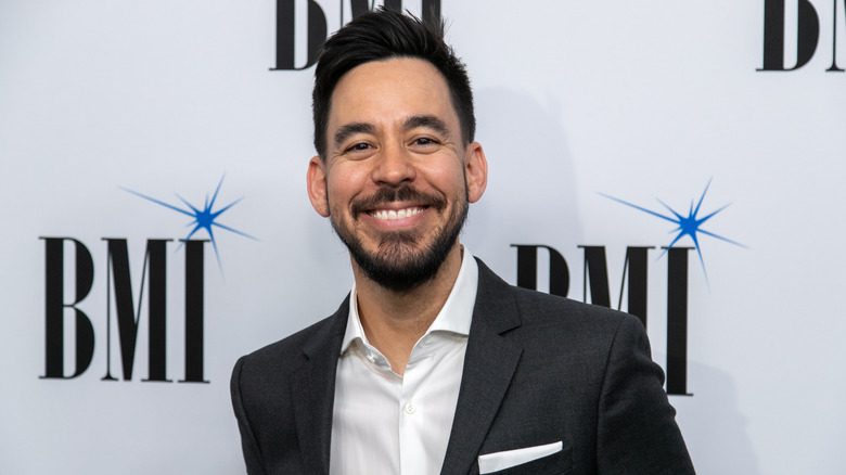 Mike Shinoda souriant, portant un blazer et une chemise blanche